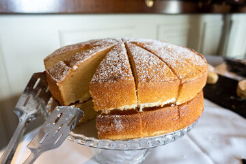 A Victoria Sponge cake cut into slices on a cake stand.