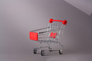 Miniature empty pushcart, customers truck, shopping trolley in mall, supermarket. Consumption, commerce, trade, shopaholism concept. Copy space.