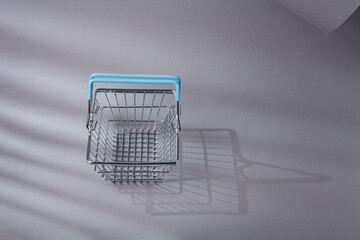 Miniature empty customers shopping basket with blue handles for supermarket. Consumption, commerce, trade, shopaholism concept. Copy space