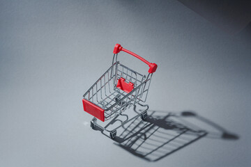 Miniature empty pushcart, customers truck, shopping trolley in mall, supermarket. Consumption, commerce, trade, shopaholism concept. Copy space.