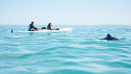 They spotted something in the deep blue water. Shot of a young couple spotting a dolphin while kayaking at a lake. © Matthew Cerff/peopleimages.com