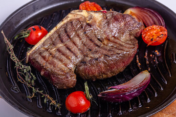 Grilled premium rib eye beef steak in the pan, cooking steak in the kitchen on a dark background, top view