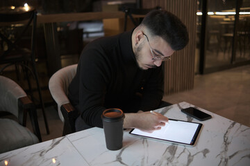 young businessman drawing with tablet in cafe