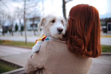 young woman spending time outside with her dog smiling and looking at her dog