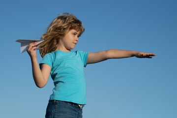 Child boy with paper plane against blue sky. Child dreaming, throwing paper plane, toy airplane. Imagination, kids freedom.