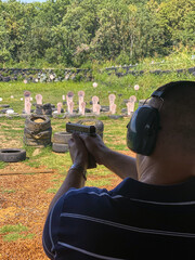 Man firing pistol at target in outdoor shooting range © SDF_QWE