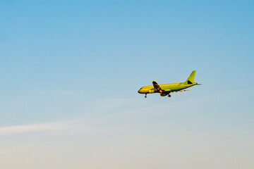 Green passenger plane against the blue sky.