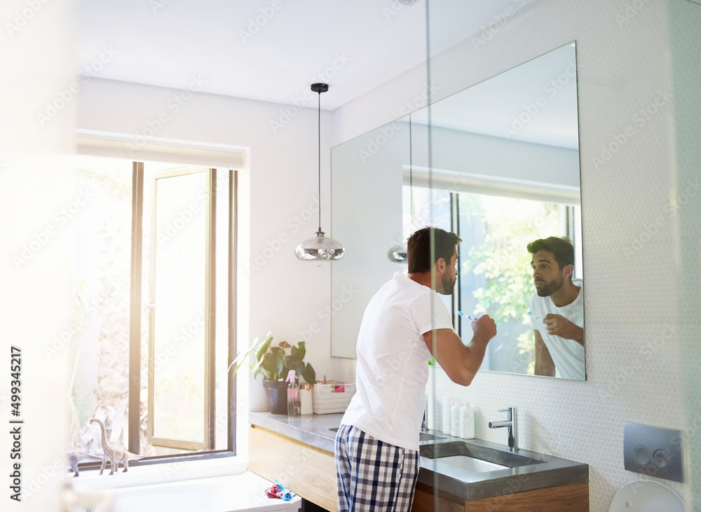 Poster twice a day keeps the dentist away. cropped shot of a handsome man looking in the mirror and rinsing