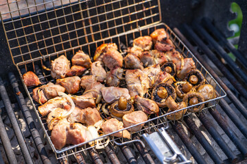 Pork skewers and mushrooms are cooked over an open fire. 