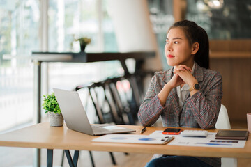 Asian businesswoman working on laptop computer and graph document calculator in the modern office...
