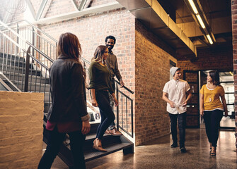 The hustle and bustle of the office. Full length shot of a group of young designers walking through...