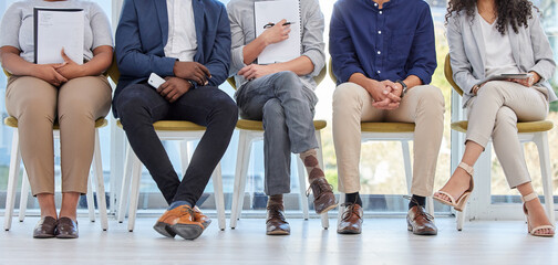 Please wait your turn. Closeup shot of a group of businesspeople sitting in line in an office.