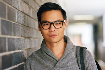 Fototapeta premium Im here to get my learn on. Cropped portrait of a handsome young male university student standing in a campus corridor.