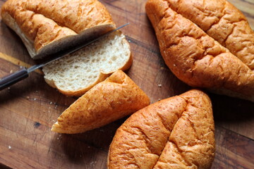 wheat bolillos made from wheat being sliced and ready to serve On a wooden cutting board at the kitchen table. Flat-lat photo.
