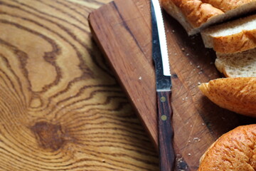 wheat bolillos made from wheat being sliced and ready to serve On a wooden cutting board at the kitchen table. Flat-lat photo.