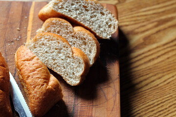 wheat bolillos made from wheat being sliced and ready to serve On a wooden cutting board at the kitchen table. Flat-lat photo.