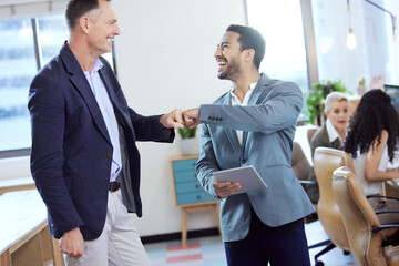 I support you. Shot of two young businesspeople giving each other a fist bump in an office at work.
