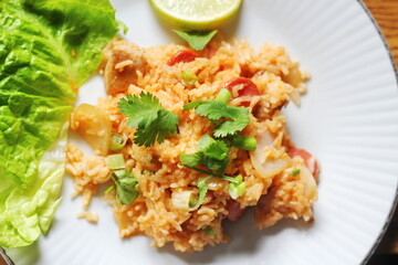 Vertical picture, pork and sausage fried rice served in a plate with lettuce and coriander garnish. Fried rice is a street food that is sold in Thailand.