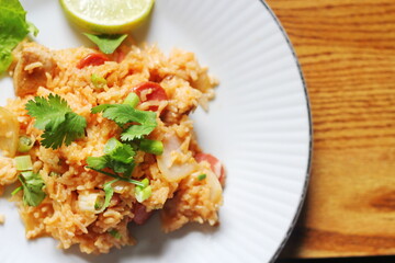 Close-up, pork and sausage fried rice served in a plate with lettuce and coriander garnish. Fried rice is a street food that is sold in Thailand.