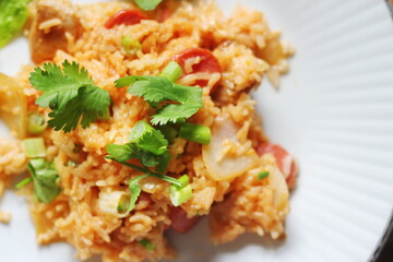Close-up, pork and sausage fried rice served in a plate with lettuce and coriander garnish. Fried rice is a street food that is sold in Thailand.