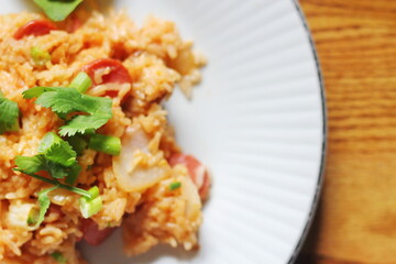 Close-up, pork and sausage fried rice served in a plate with lettuce and coriander garnish. Fried rice is a street food that is sold in Thailand.