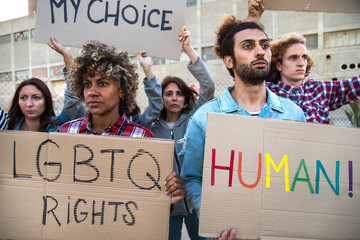 Multiracial group of people march together protesting on a demonstration for LGBT rights holding...