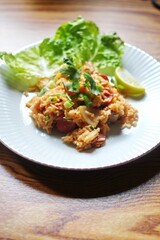 Vertical picture, pork and sausage fried rice served in a plate with lettuce and coriander garnish. Fried rice is a street food that is sold in Thailand.