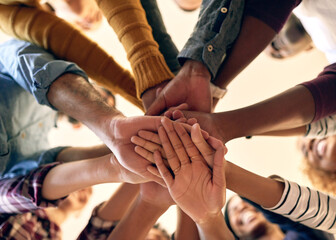 Joining their strengths in unity. Low angle shot of a group of people joining their hands together.