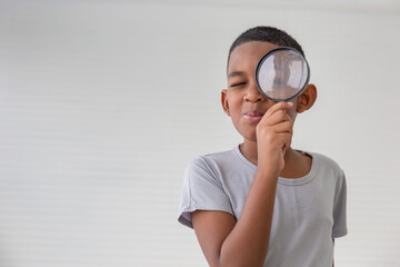 Boy holding the magnifying glass, Little kid boy holding and looking through magnifying glass showing a big eye © iPoguz
