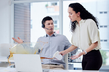 How clumsy can you be. Shot of a businesswoman spilling a cup of coffee over a colleagues desk in a...