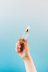 A mockup of a cosmetic bottle with a facial serum in a woman's hand.