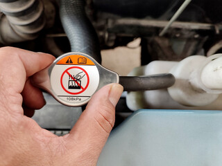 A man is going to check the radiator of a car.