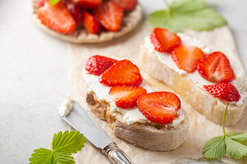 Strawberries sandwiches with cream cheese and on paper, light background