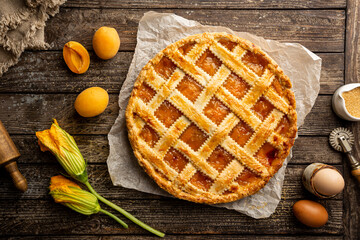 Summer apricot or peach pie homemade on wooden background, top view. Delicious fruit dessert. Fruit...