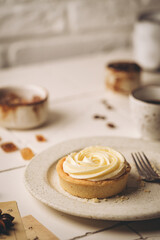 Mini tart with whipped cream and lemon, sweet dessert on white plate