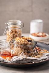 Delicious homemade granola in glass jar on gray background. Breakfast. Healthy food sweet dessert snack. Diet nutrition concept. Vegetarian food.