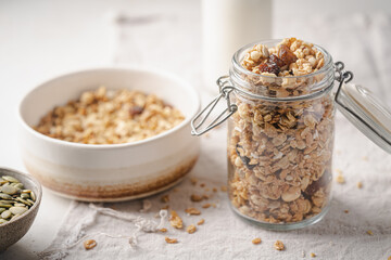 Delicious homemade granola in glass jar on white background. Breakfast. Healthy food sweet dessert snack. Diet nutrition concept. Vegetarian food.