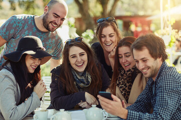 Thats just the funniest video ever. Cropped shot of a group of friends looking at something funny on a cellphone.