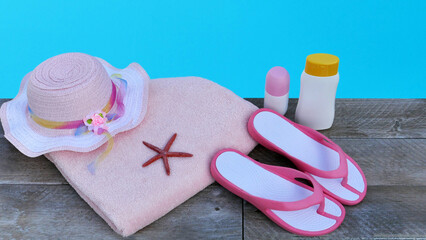 Schwimmbadzubehör flach liegend. Flip Flops, sonnencreme, Handtuch, Hut, und Sonnenbrille mit Platz für Text an einem Schwimmbadrand liegend.