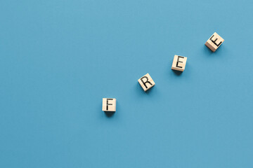 Wooden cubes with the inscription free on a blue background. Flat lay. Copy space. Business concept