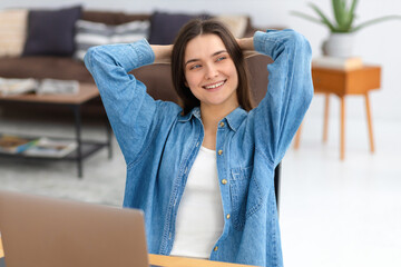 Happy smiling Caucasian woman freelancer with laptop resting with hands behind head distracted from...