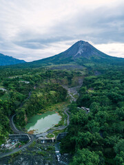 The view of Mount Merapi with the Bebeng River and a lake that holds water, the sky looks cloudy. Forest with dense of trees surrounding the lake also See Mt. Merbabu from a distance. Bego Pendem