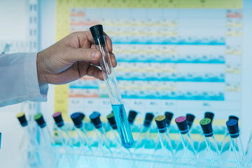 Portrait of a scientist working in the lab examines a test tube with liquid.