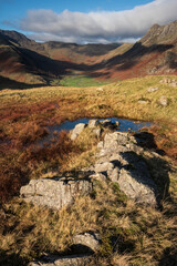 Colorful vibrant Autumn landscape image looking from Pike O'Blisco towards Langdale Pikes and Range with beautiful sungiht on mountains and valley
