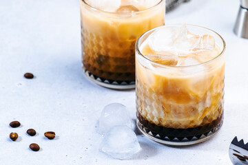 Trendy alcoholic cocktail drink with vodka, coffee liqueur, cream and ice, gray background, bar tools