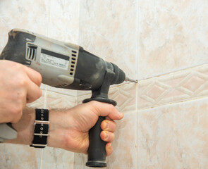 the builder in the bathroom using a hammer drill holes to install shelves