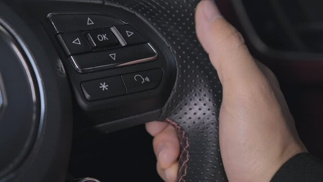 Close-up Hand of a female driver in a suit pressing button to enable or disable the voice command function on the steering wheel while driving. Concept of transportation and technology.