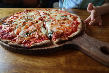 child eating delicious pizza on the wooden plate close-up