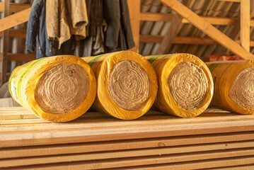 Insulation rolls in yellow packaging in the attic of a wooden house. r