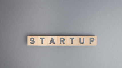 Startup business concept,  Text STARTUP on wooden block over grey background.